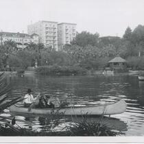 People on boats at the lake with a view of Ansonia Apartments, Westlake Park otherwise known as MacArthur Park, Los Angeles