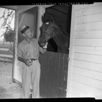Fred Astaire with horse in stall at ranch in Los Angeles, Calif., circa 1953