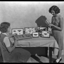 Two school girls at Thomas Starr King Junior High School show a butterfly collection, Los Angeles, circa 1933