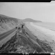 Woman standing on embankment of the Pacific Coast Highway between Long Beach and Huntington Beach, 1929