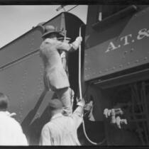Crown Prince Gustav Adolf of Sweden clibing into in the cab, or engineer's compartment, of a train, [Los Angeles?], 1926
