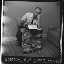 Writer Vernon Howard leaning against stacks of his self improvement books