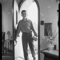 Young man with books coming through doorway, Santa Monica, [1940s?]