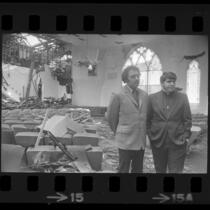 Reverend Troy Perry and Jerry Small standing amid fire damage at Metropolitan Community Church in Los Angeles, Calif., 1973