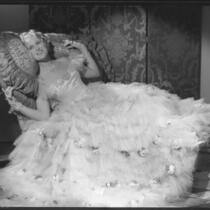 Peggy Hamilton modeling a Travis Banton gown with a full skirt of white tulle accented with gardenias, 1933