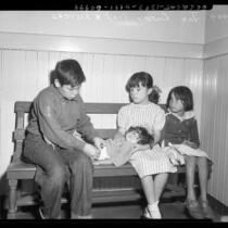 Four destitute Mexican American children sitting on bench Los Angeles, Calif., circa 1953