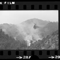 DC-6 airplane dropping fire retardant on wildfire near Mount Baldy Village, Calif., 1975
