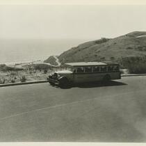 A bus driving on a road overlooking the ocean