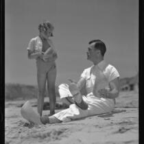 Actor Neil Hamilton and daughter Patricia on beach holding wooden shoes, Malibu, 1937