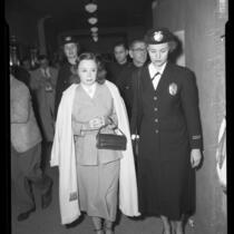 Burlesque dancer Betty Rowland, (aka Ball of Fire) being escorted by policewoman June Howard after being convicted of lewd conduct in Los Angeles, Calif., 1952