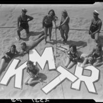 Young people on beach promoting radio station KMTR, Santa Monica, [1925-1946]
