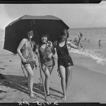 Young women posing on beach with umbrella and seaweed, Pacific Palisades, 1927