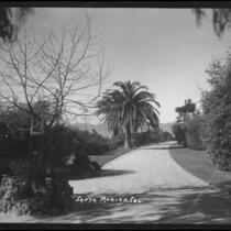 View of Palisades Park with couple seated on bench on left side of wide walkway, Santa Monica, circa 1915-1925