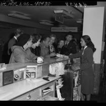 Actors Marsha Hunt, Humphrey Bogart, Lauren Bacall and others at airport ticket counter on way to Washington D.C. to see Un-American Activities Committee