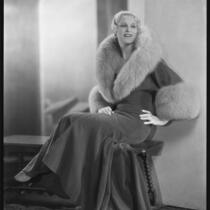 Peggy Hamilton modeling an Adrian full-length coat trimmed with fur, circa 1929-1933