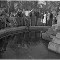 Man jumps into a fountain on USC's campus while a crowd watches, Los Angeles, 1946