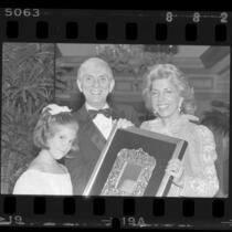 Aaron and Tori Spelling with Les Dames de Champagne president, Toni Webb posing with Host of Year award in Los Angeles, Calif., 1985