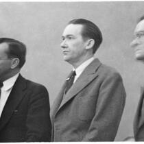 Murder suspect Robert S. James standing between two unidentified men in court, Los Angeles, 1936