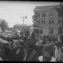 University of Southern California graduation ceremony, graduates and faculty surrounding stage with unveiled Trojan Statue, 1930
