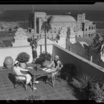 Vacationers on sunny terrace overlooking the coast of Southern California and fleet of ships, Long Beach 1932