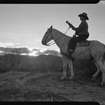 Cowboy on horse with guitar at sunset, Palm Springs, [1930s or 1940s?]