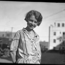 1/2 length portrait of Nita Carson standing on street smiling in Los Angeles, Calif., 1925
