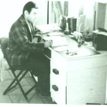 Charles Kikuchi writing at desk at Gila River, AZ., circa 1943