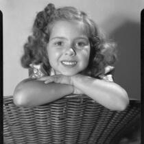 Sylvia Arslan leaning on wicker chair, 1937