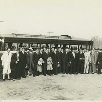 A group of men standing in front of a parked bus