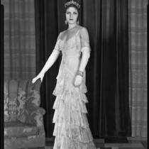 Woman modeling a lace evening gown and crown, circa 1928-1933