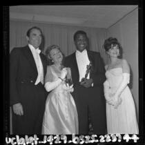 Sidney Poitier holding his Oscar poses with Gregory Peck , Annabella and Anne Bancroft backstage at 1964 Academy Awards