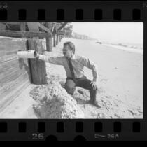 Robert Saviskas, health officer, inspecting pipe on Malibu beach home, 1986