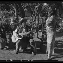 Eugene R. Plummer with guitar and Indian artifacts, with woman in shawl, Hollywood, 1927