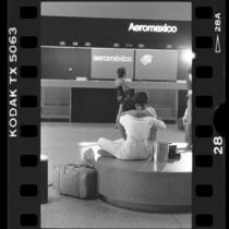 Latino couple comforting each other at LAX after learning of Aeromexico plane crash, 1986