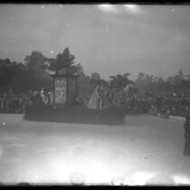 1928 Rose Parade spectators watching Sherman Institute's float depicting scenes of American Indians