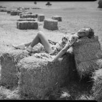 Mrs. Joe Raymond reclining on baled hay, San Fernando Valley, 1946