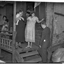 Poverty-stricken family speaks to unidentified man outside of their dilapidated home, Los Angeles, 1930s