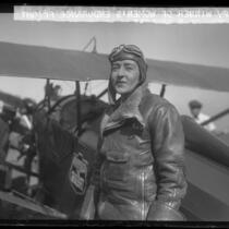 Bobbi Trout in flight suit standing beside her plane at Mines Field after setting women's endurance record, Los Angeles, Calif., 1929