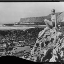 Young woman posing on rocks overlooking beach, Malibu, 1929