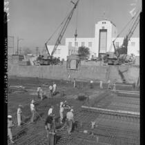 Cranes swing large cement buckets of concrete to foundation floor of city hall in Burbank, Calif., 1960