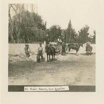 Woman, men, child and horses in front of white picket fence on Haas Ranch.