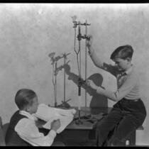 Two school boys at Thomas Starr King Junior High School demonstrate a science experiment, Los Angeles, circa 1933