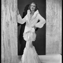 Actress Loretta Young modeling a white ermine spring jacket over a pale pink ruffled net gown, 1931