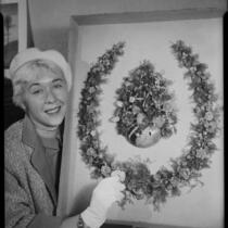 Dane Gorrell with 1888 horseshoe-shaped shell art wreath made by poet Ina Donna Coolbrith, Santa Monica, 1953