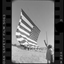 Rancher Bob Older watching unfurling of 67x102 foot American flag for U.S. bicentennial in Oro Grande, Calif., 1976