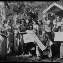 Mrs. Flournoy and group posing in front of house with architectural plans, [1950s?]