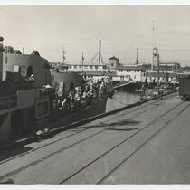 ship workers look on at train carting goods, San Pedro Harbor