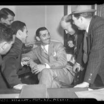 Actor Clark Gable seated, surrounded by group of five men, circa 1937