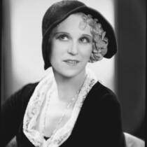 Peggy Hamilton modeling a hat of black soleil with hemstitched border and felt rose petals, 1930