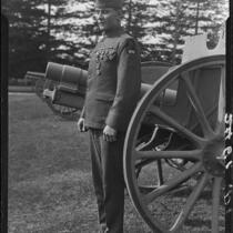 Veteran Robert W. Renton, in uniform with medals, standing in front of row of cannons, Los Angeles, 1928 or 1930